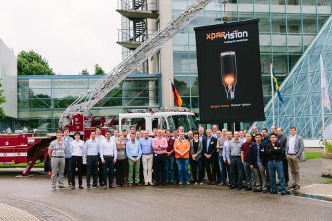 Professionals gathering under the XPAR Vision Seminar banner lifted high by the ladder of a beautiful historical American firetruck.